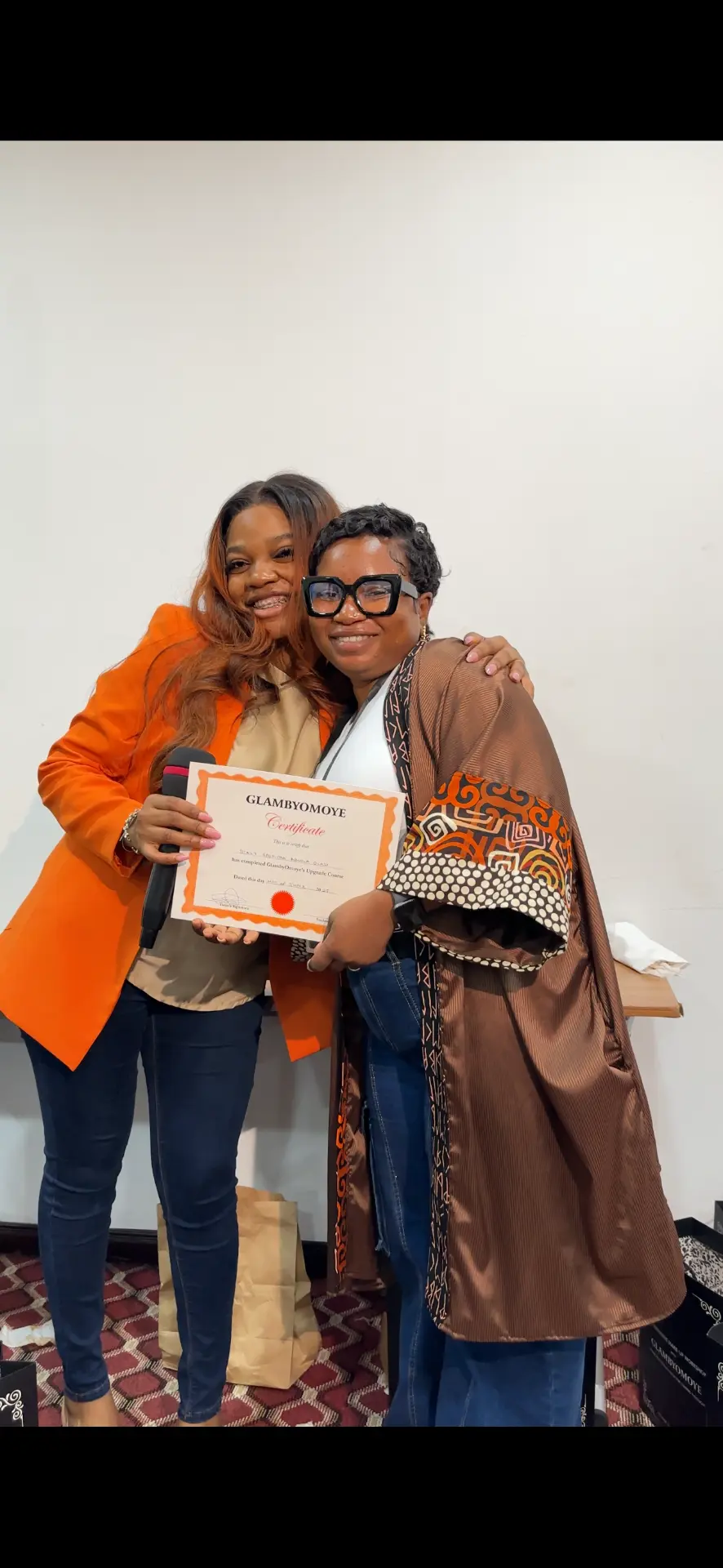 Omoye celebrating with a graduate holding her certificate
